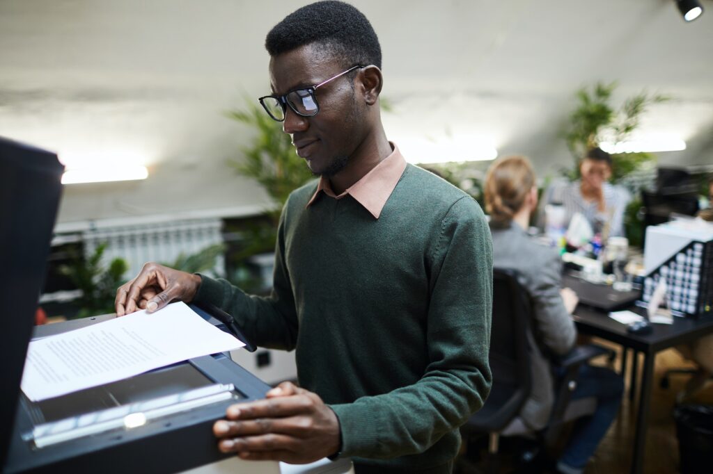 African Intern Using Scanner in Office